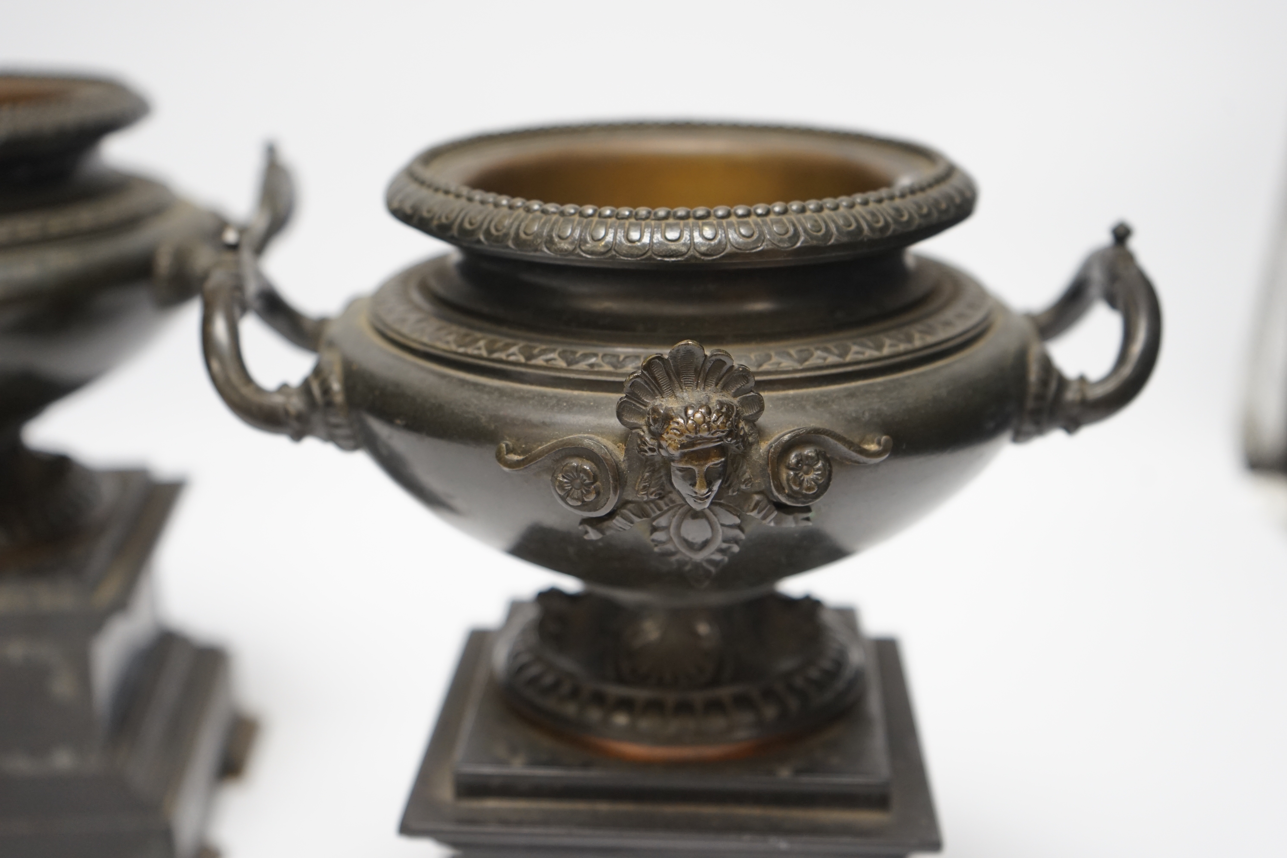 A pair of 19th century bronze urns on slate pedestals, 21.5cm high